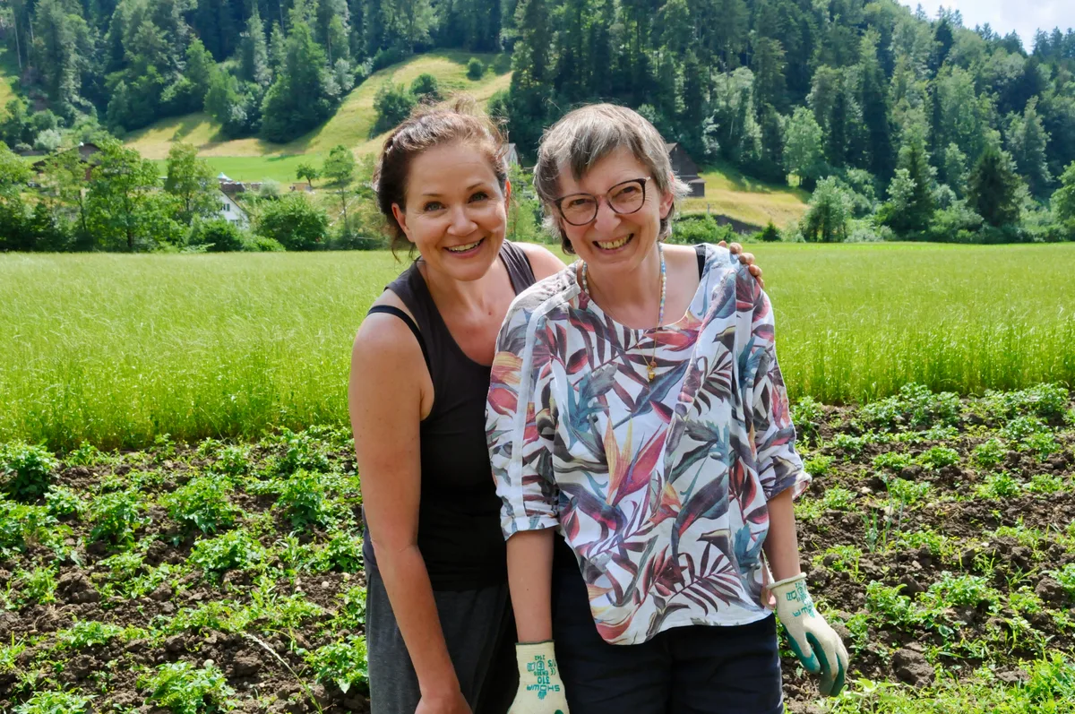 Man sieht zwei Gärtnerinnen vor dem Gemüsefeld.